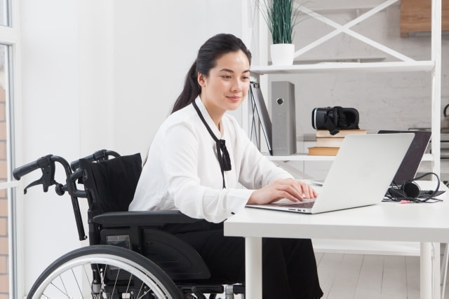 車椅子の女性がパソコンで仕事をしている